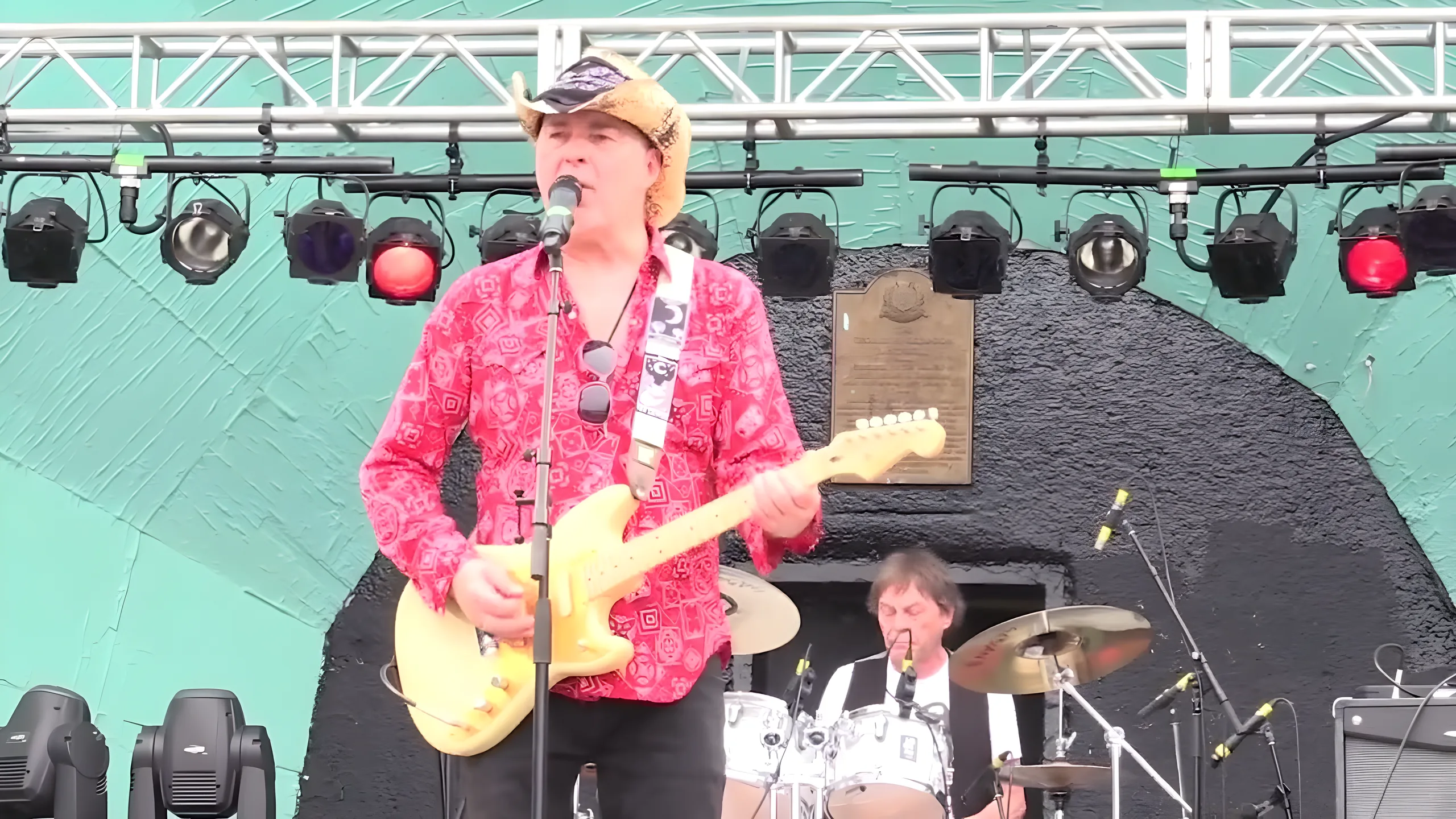 Tim Gibbons on an outdoor festival stage in a red paisley shirt